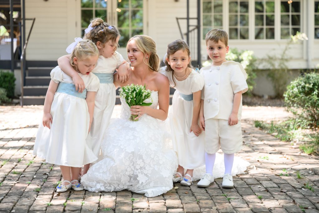 Bride smiling with young flower girls and a ring bearer outside Mattie’s at Green Pastures in Austin